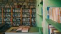 Libri aperti su un tavolo davanti agli scaffali di una biblioteca