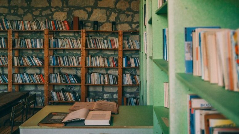 Libri aperti su un tavolo davanti agli scaffali di una biblioteca